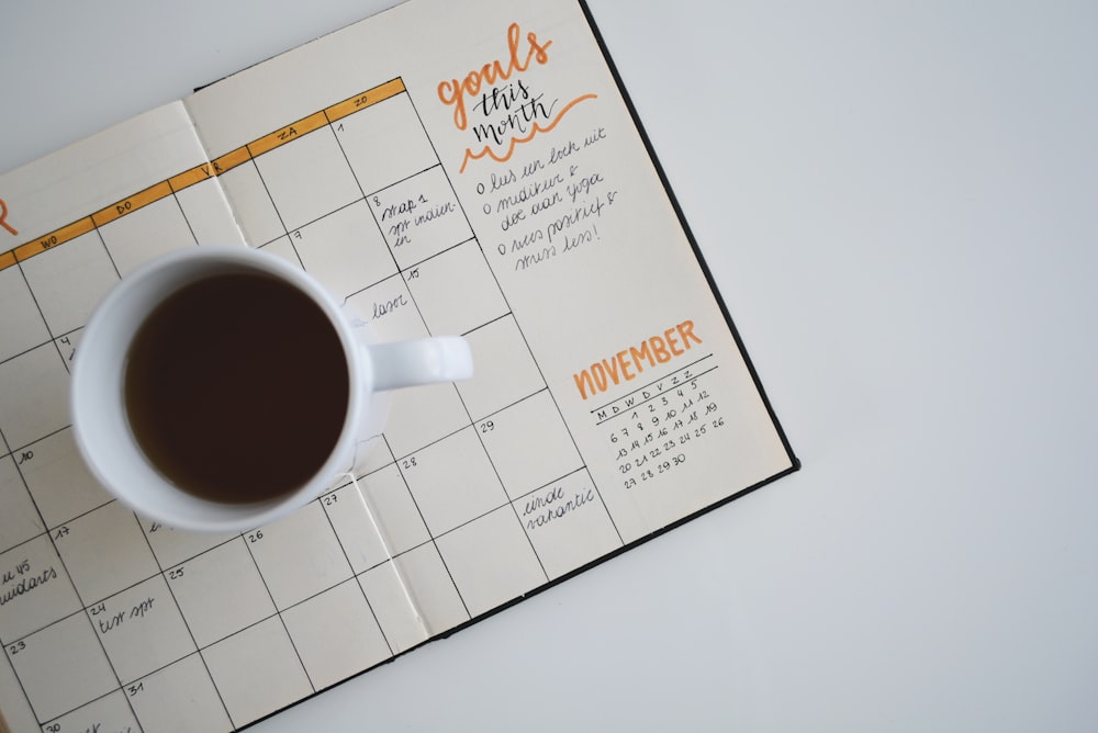An open monthly planner with a cup of coffee and handwritten goals